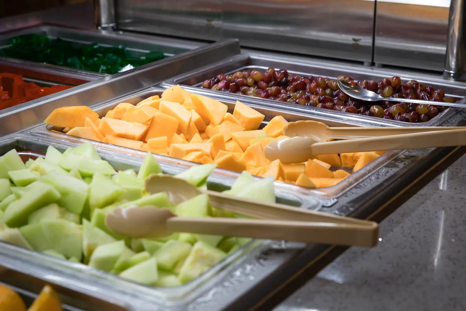 Fresh fruit buffet with honeydew melon, cantaloupe, and red grapes
