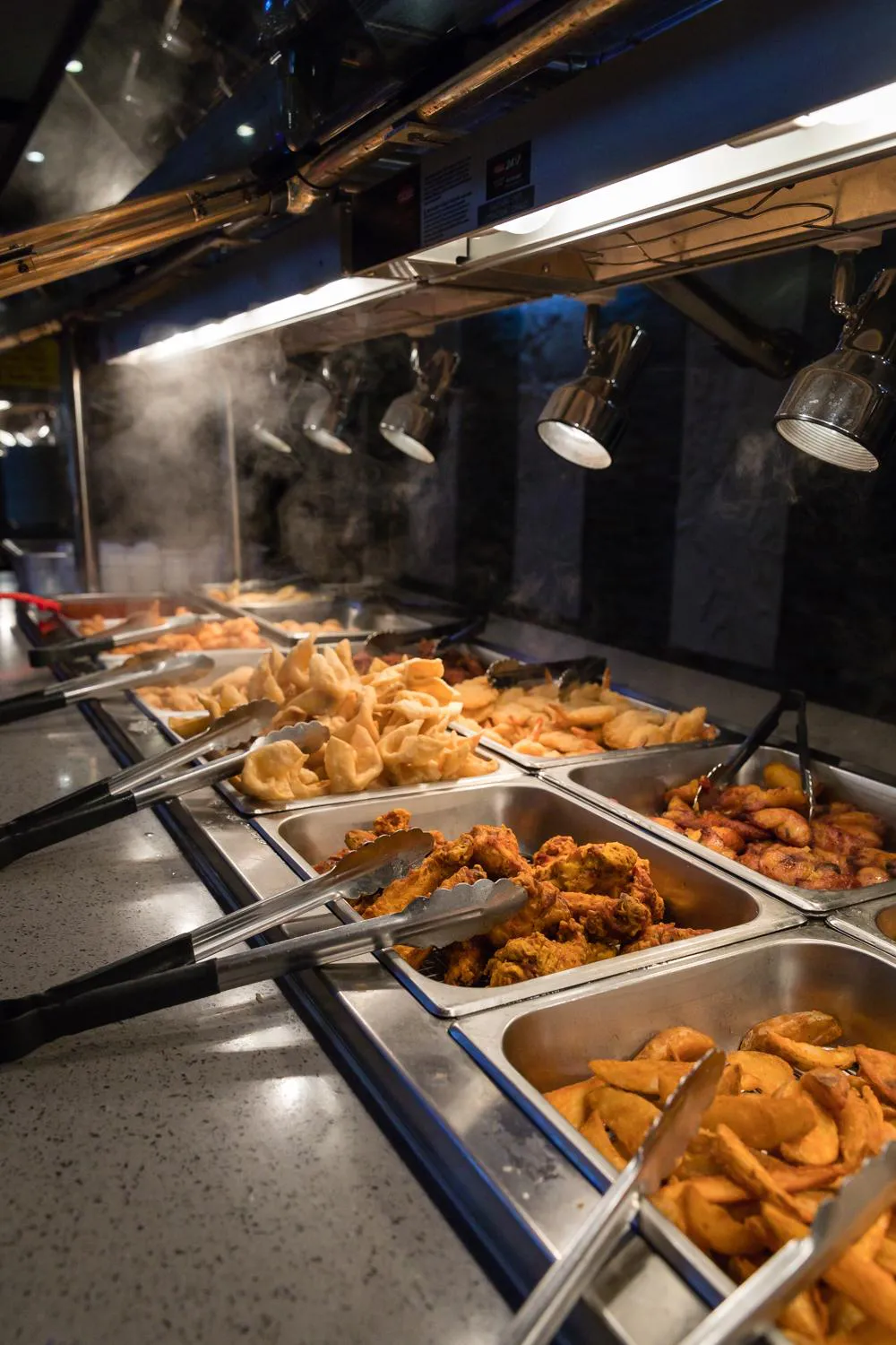 Hot buffet station with fried chicken, wontons, spring rolls, and other appetizers