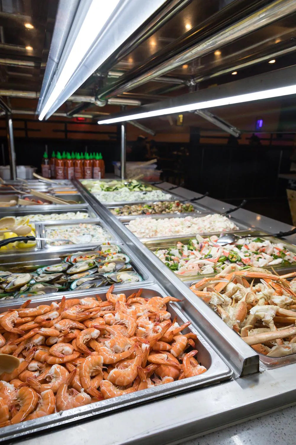 Seafood buffet with trays of shrimp, crab legs, mussels, and cold salads